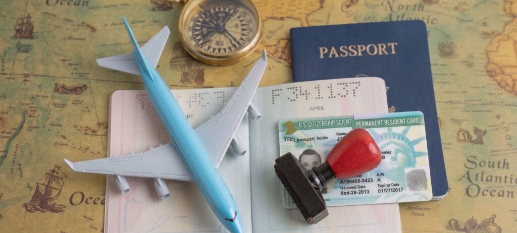 A successful EB-3 employment-based green card application illustrated: Close-up view of travel documents, including an open U.S. passport and a stamped Permanent Resident Card (Green Card), on a vintage world map. Features a blue toy airplane, a vintage compass, and a red approval stamp, representing the final step for a skilled worker or professional international applicant